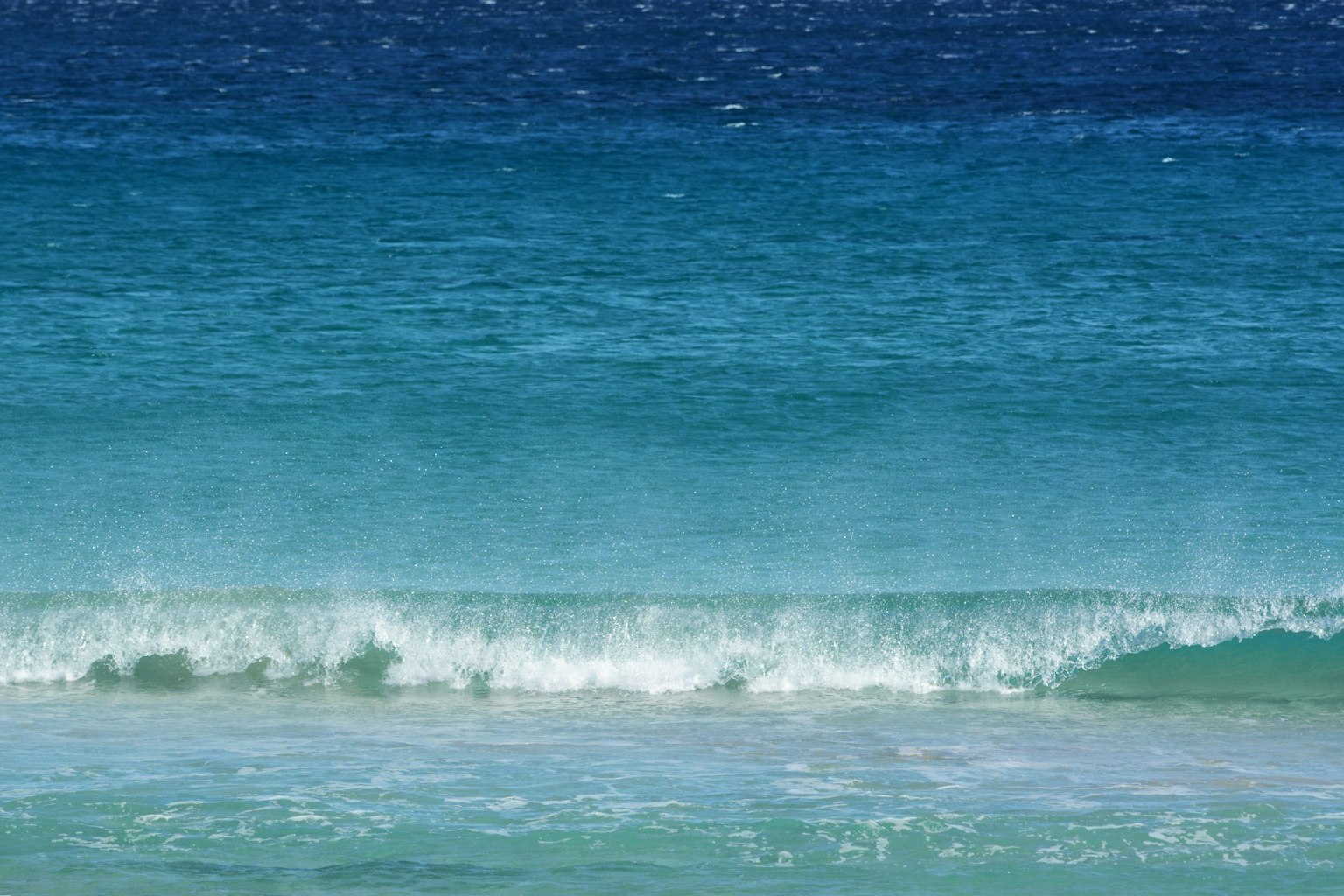 Calm waves crashing on a vibrant blue ocean