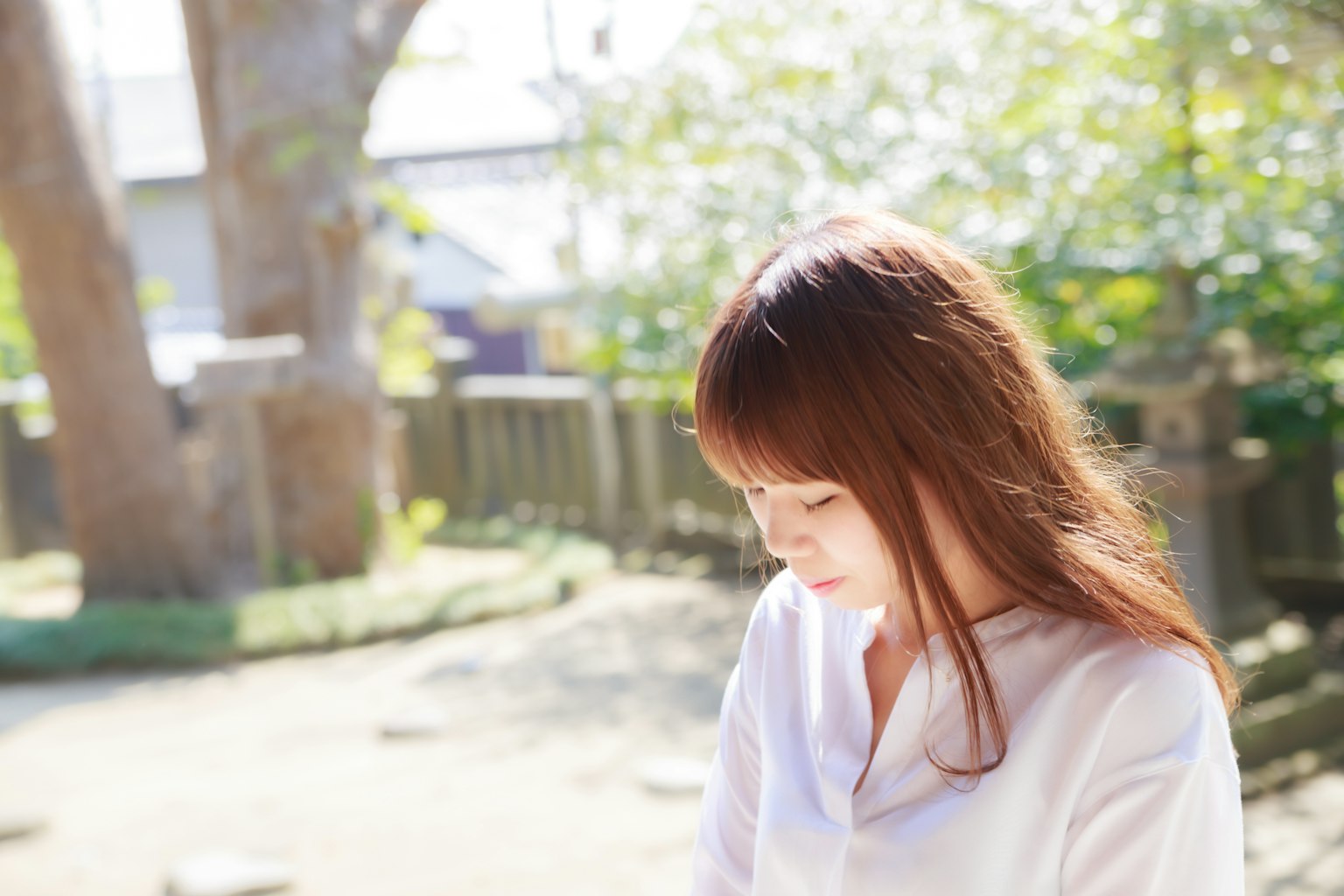 ผู้หญิงยืนอยู่ในสวนสาธารณะสวมเสื้อเชิ้ตสีขาวแสงธรรมชาติที่นุ่มนวลส่องผ่าน