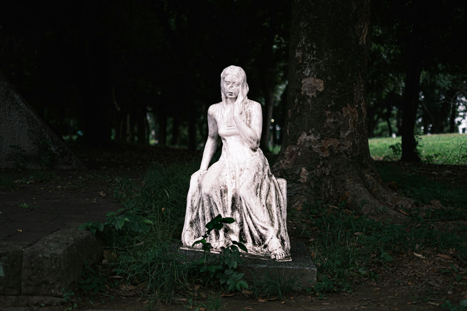 Eine weiße Skulptur einer sitzenden Frau vor einem dunklen Hintergrund