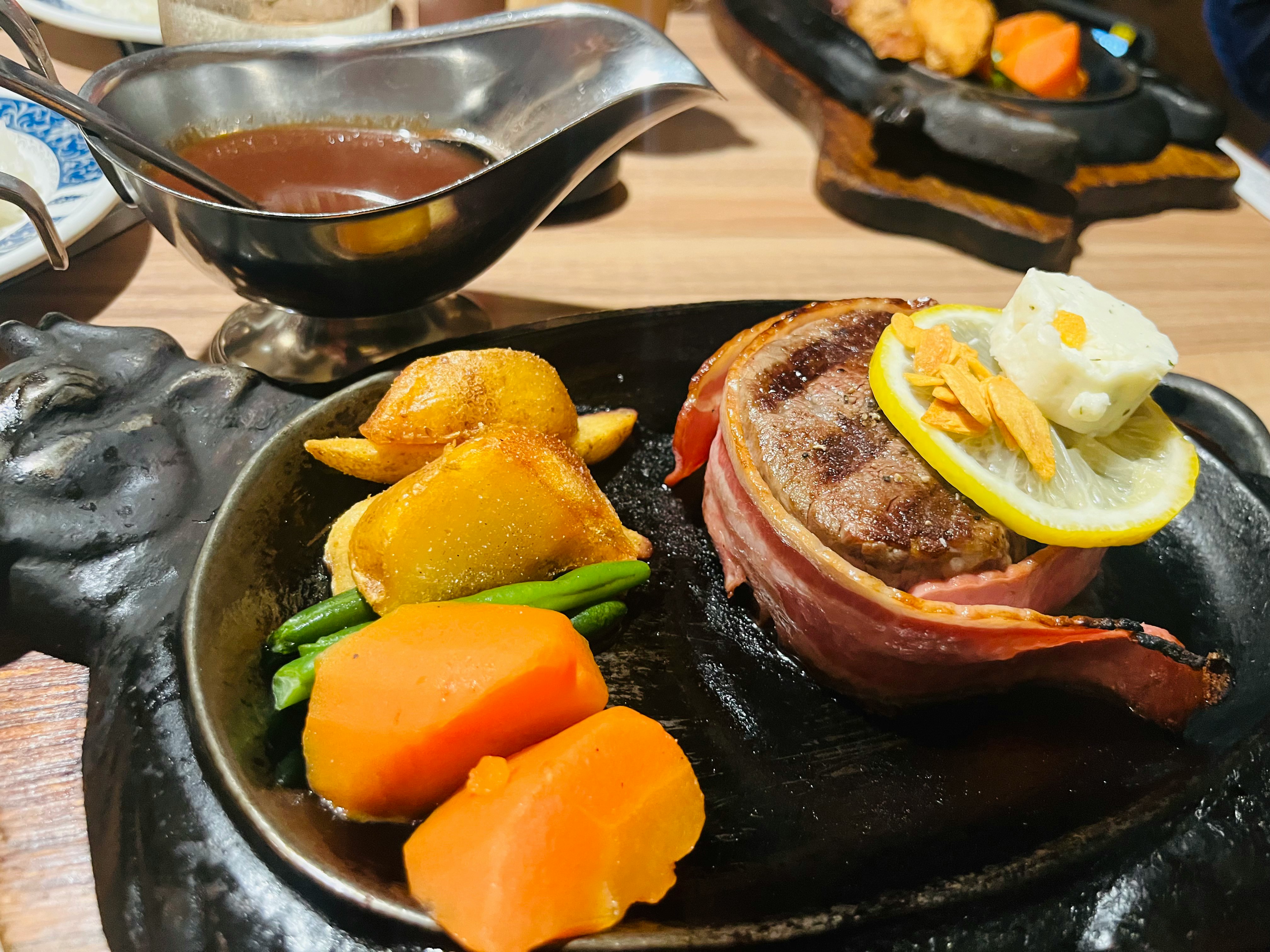 steak mendesis di atas hot plate dengan sayuran dan lemon