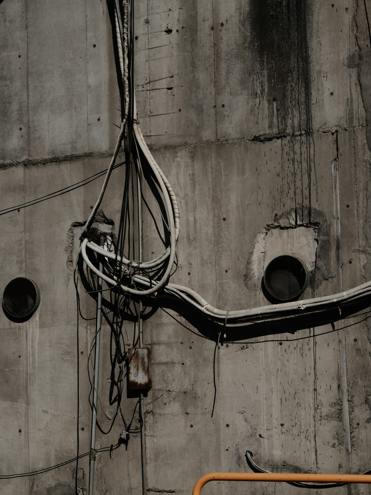 Tangled wires on a concrete wall with circular openings