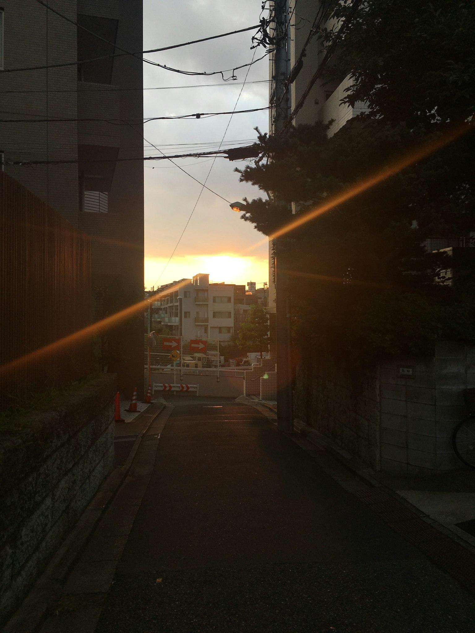 Narrow alleyway with sunlight streaming in sunset surrounded by tall buildings