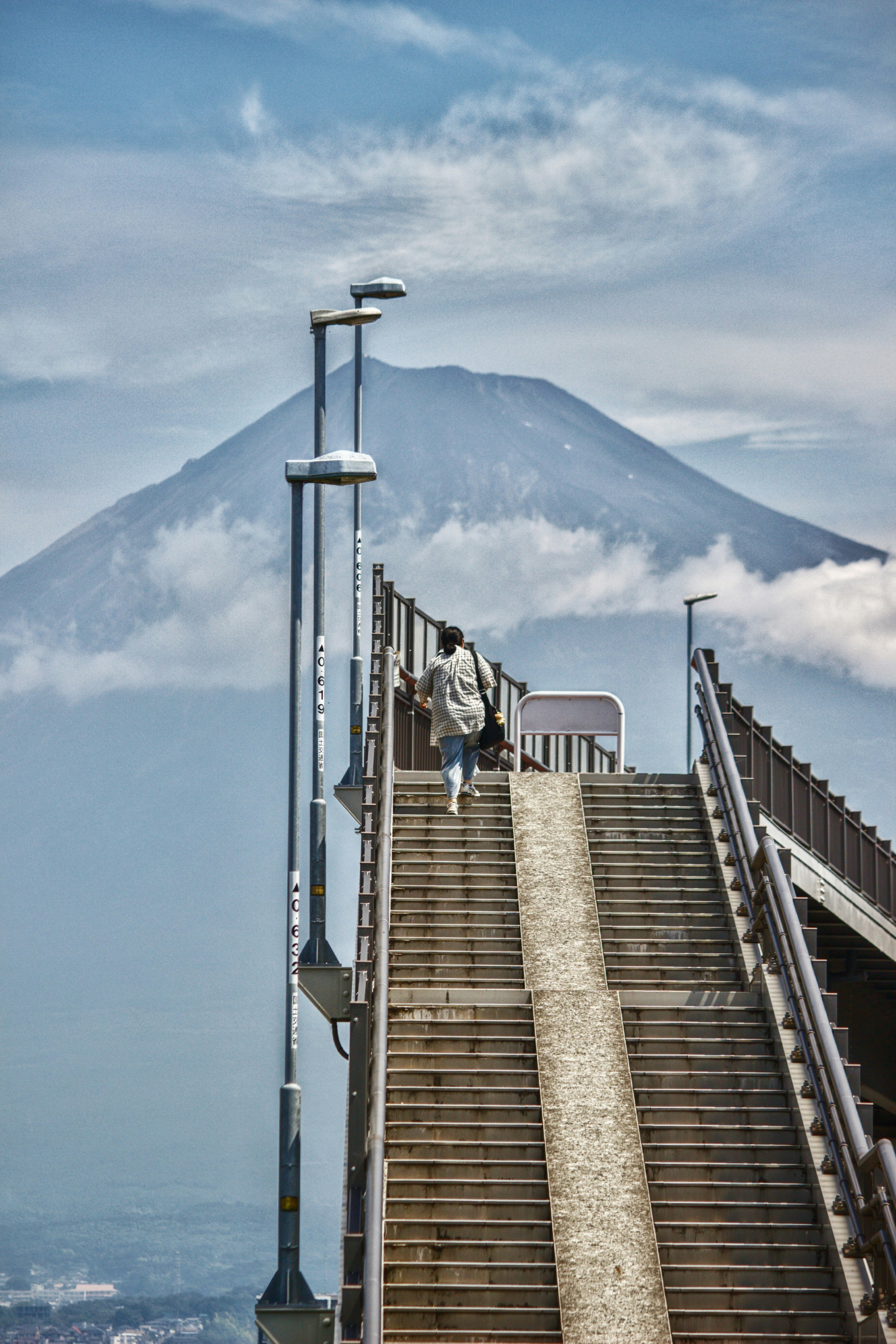 雲海の向こうにそびえる富士山を背景に階段を登る人のスナップショット