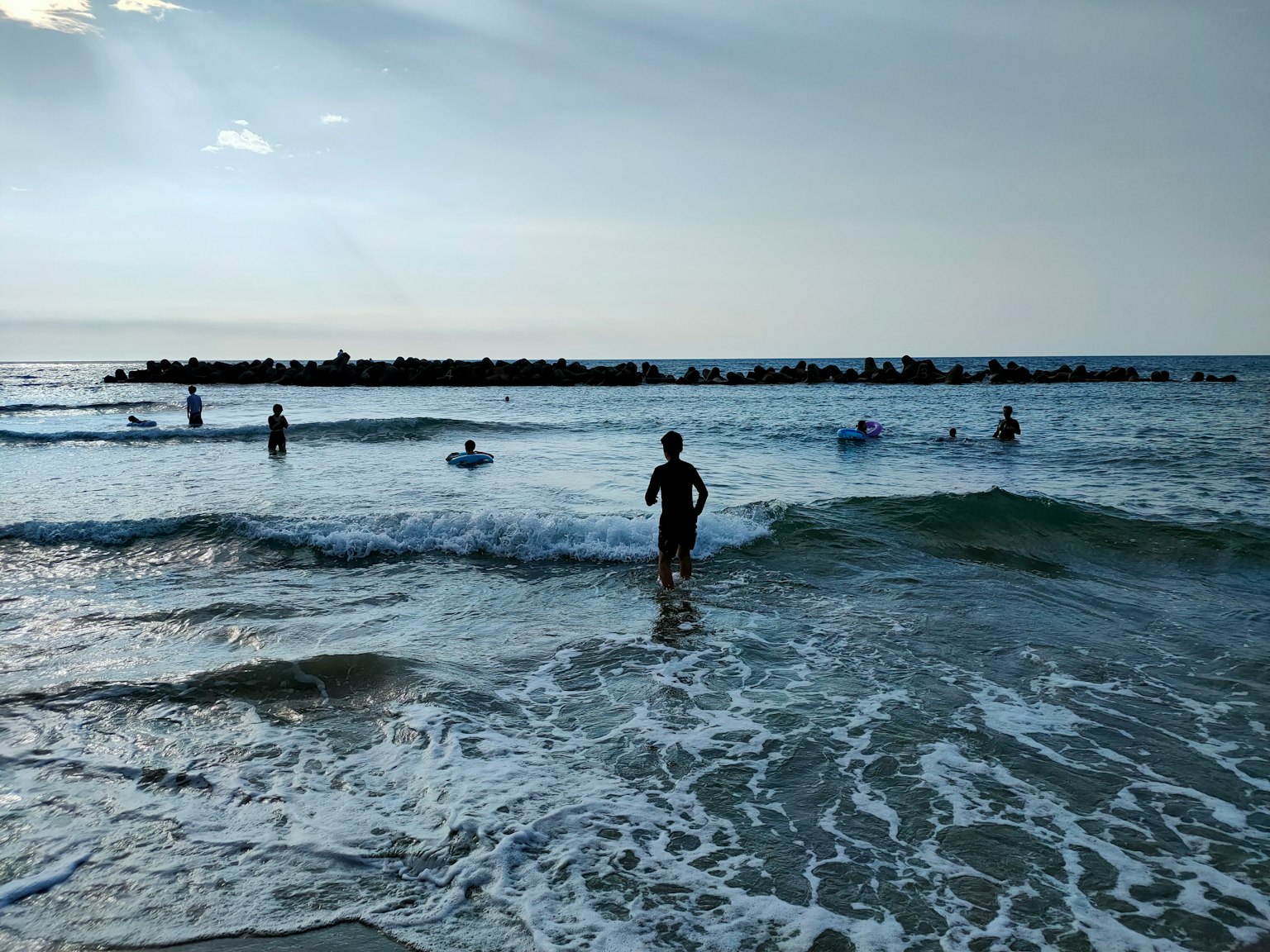 Children playing in the ocean with surfers and waves