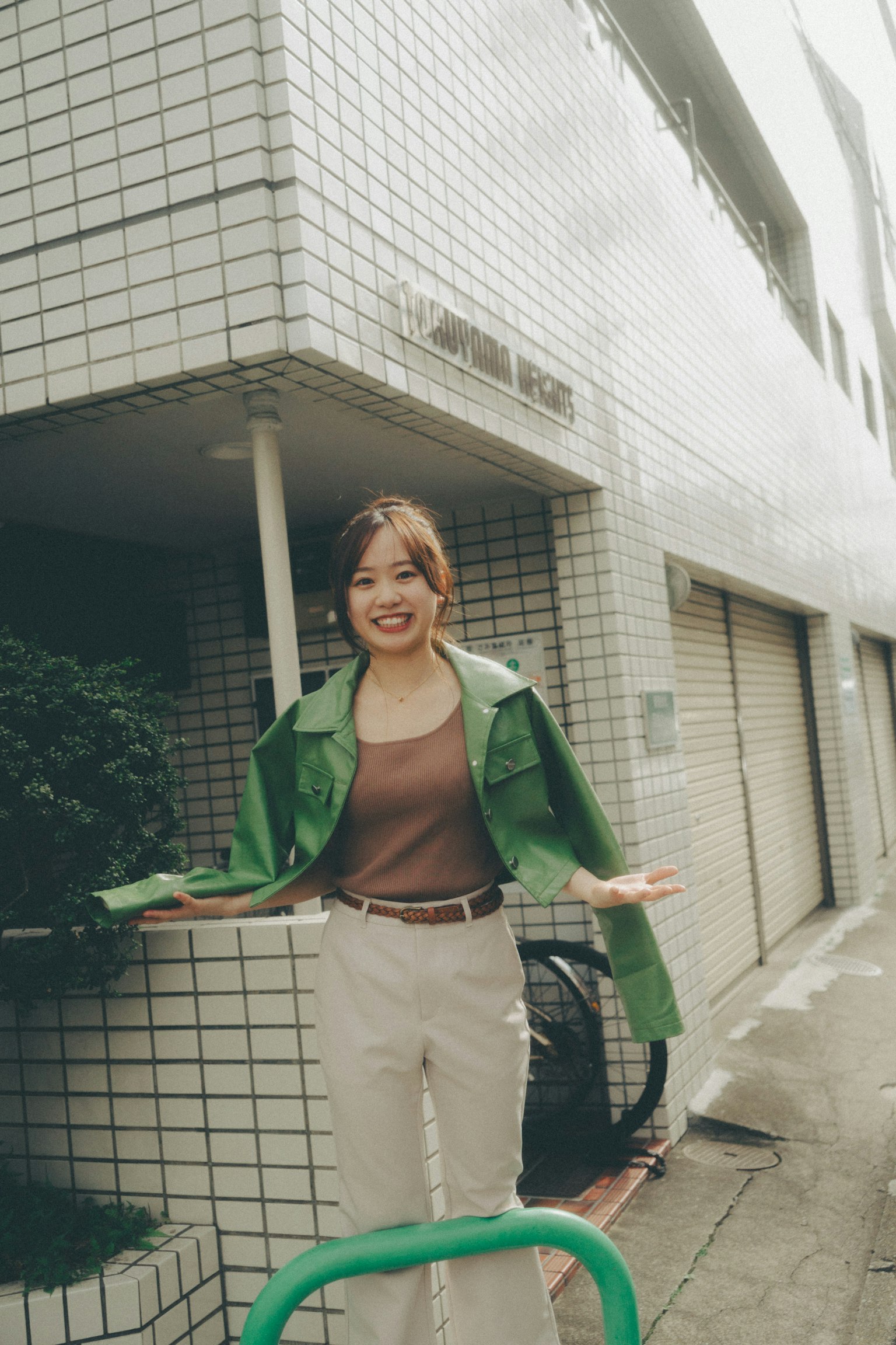 A woman in a green jacket smiling in an urban setting