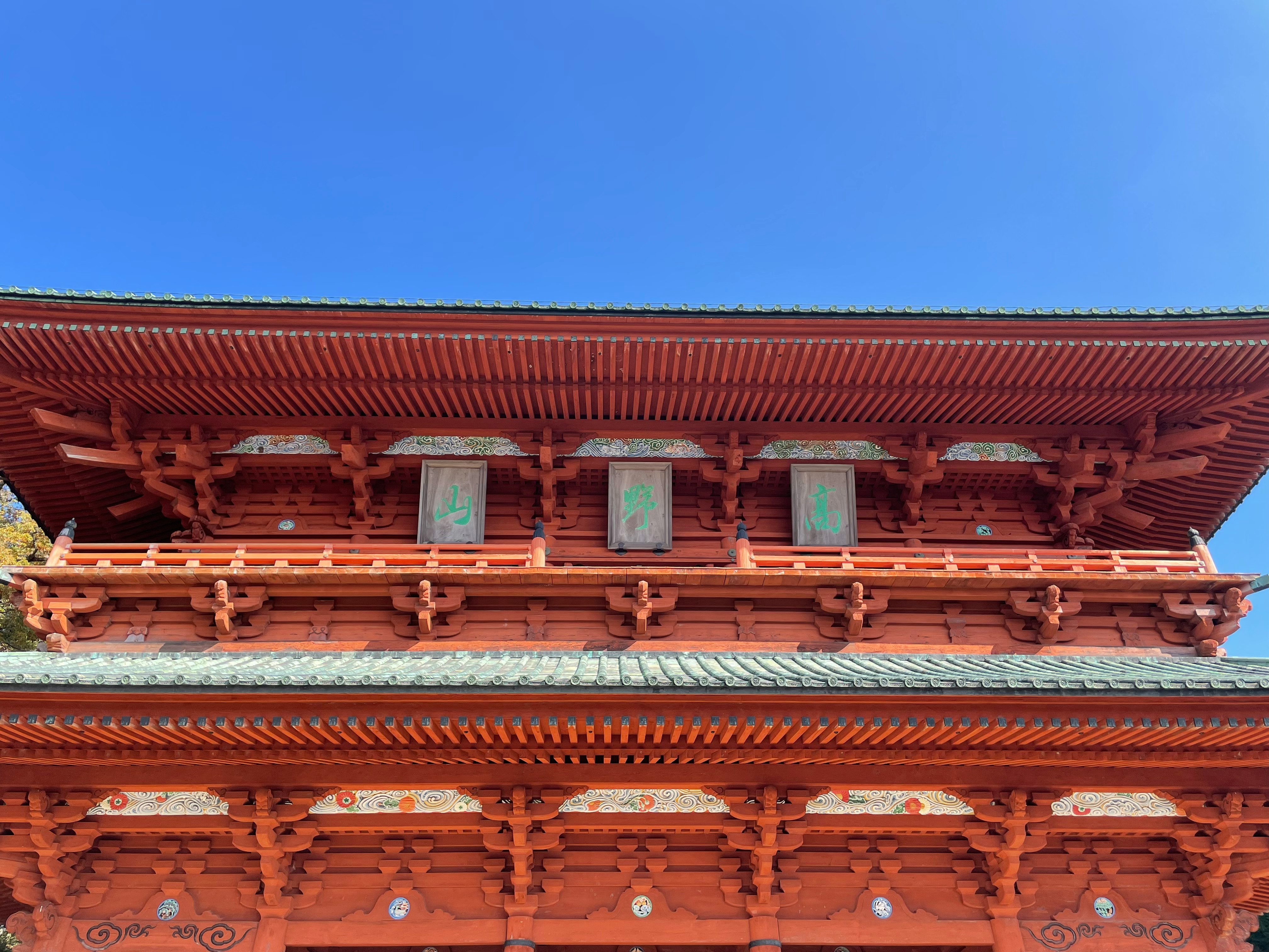 赤い木造の寺院建築の軒下と彫刻