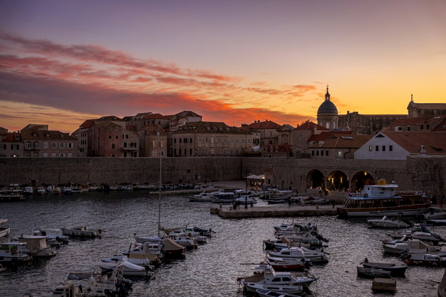 Porto di Dubrovnik al tramonto con barche e edifici storici