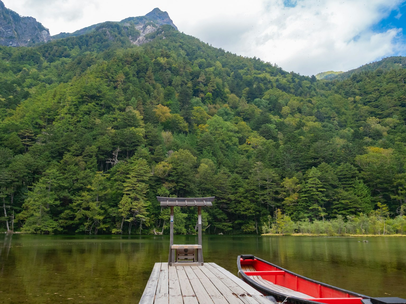 Serene lake dock surrounded by mountains with a red canoe