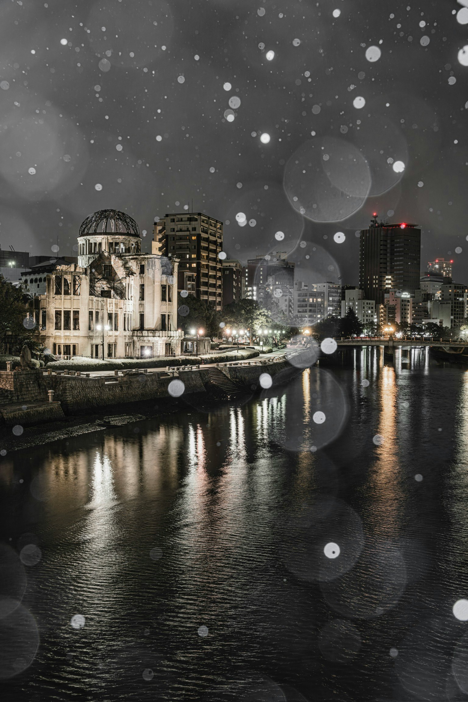 Cityscape at night with falling snow and reflections on the river