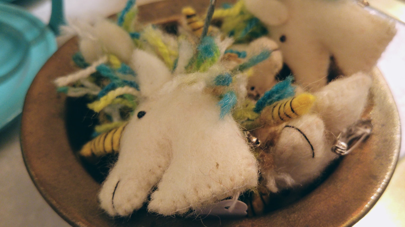 Felt unicorn decorations in a bowl with colorful accents
