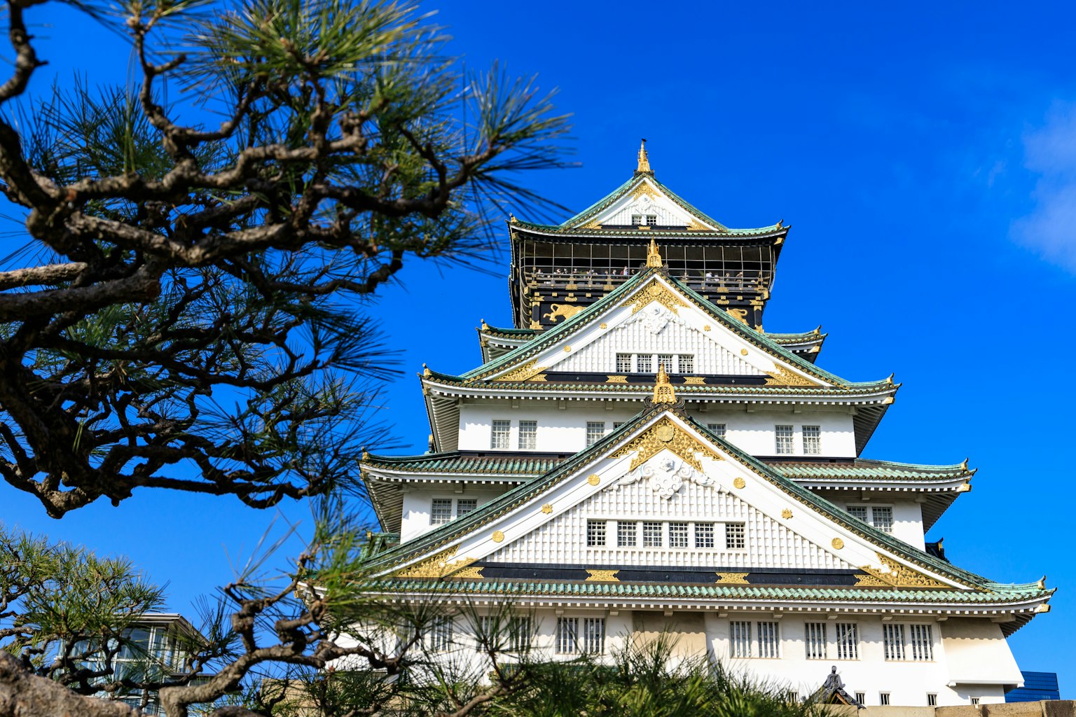 Eksterior indah Kastil Osaka di bawah langit biru dan pohon di sekelilingnya