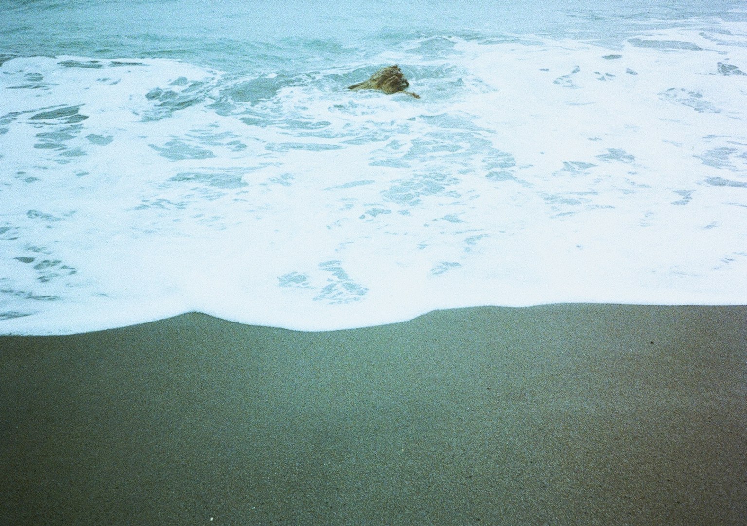 海浪拍打沙灘，岩石可見