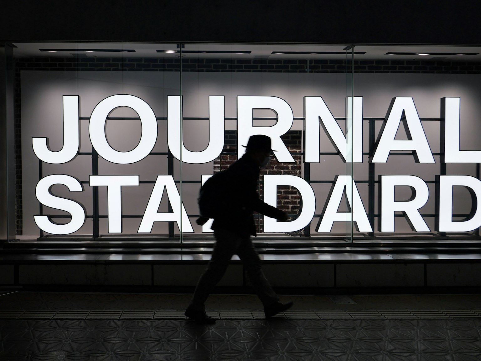 人が歩いている背景に大きな白い文字で「JOURNAL STANDARD」と書かれた看板