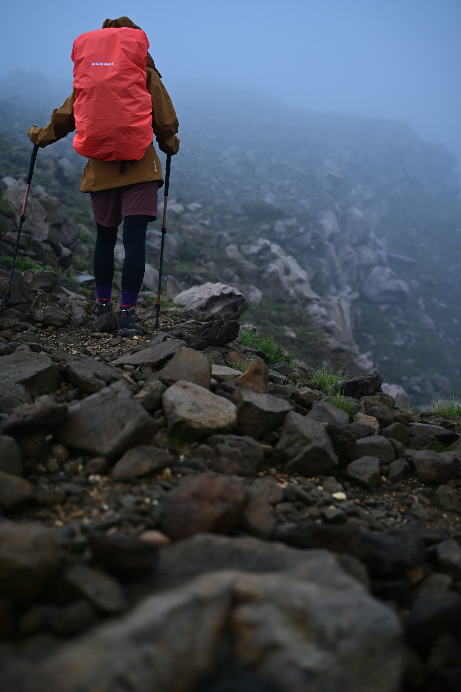 Wanderer, der durch den Nebel geht und einen roten Rucksack trägt