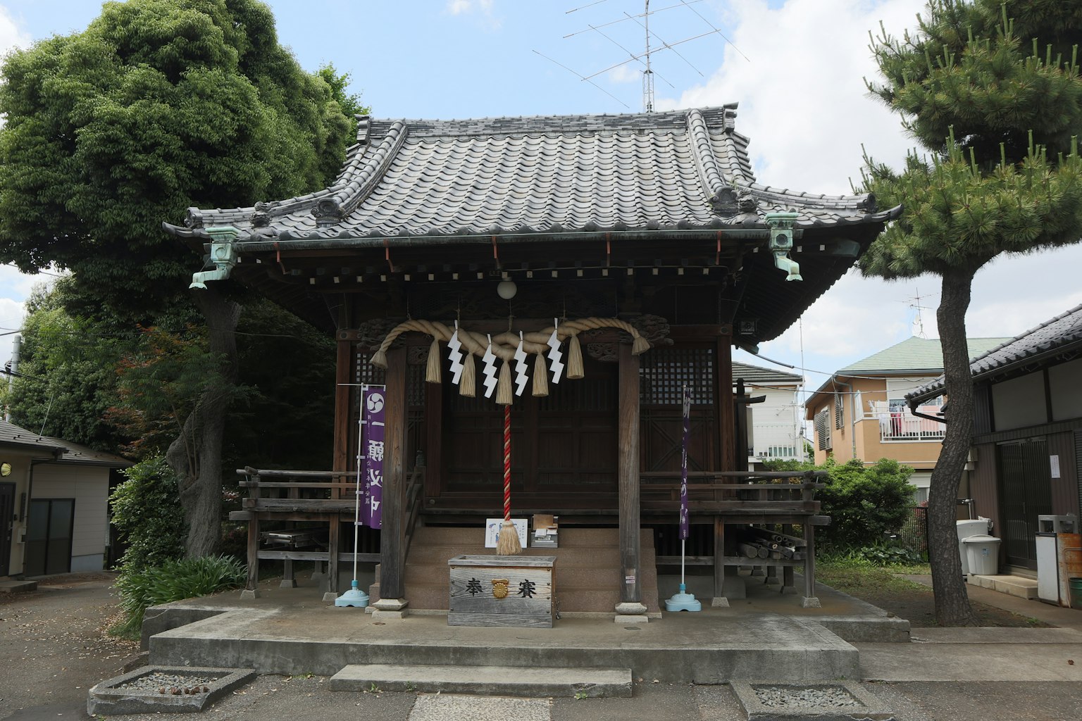 Exterior de un santuario japonés tradicional con techo de tejas y ofrendas delante
