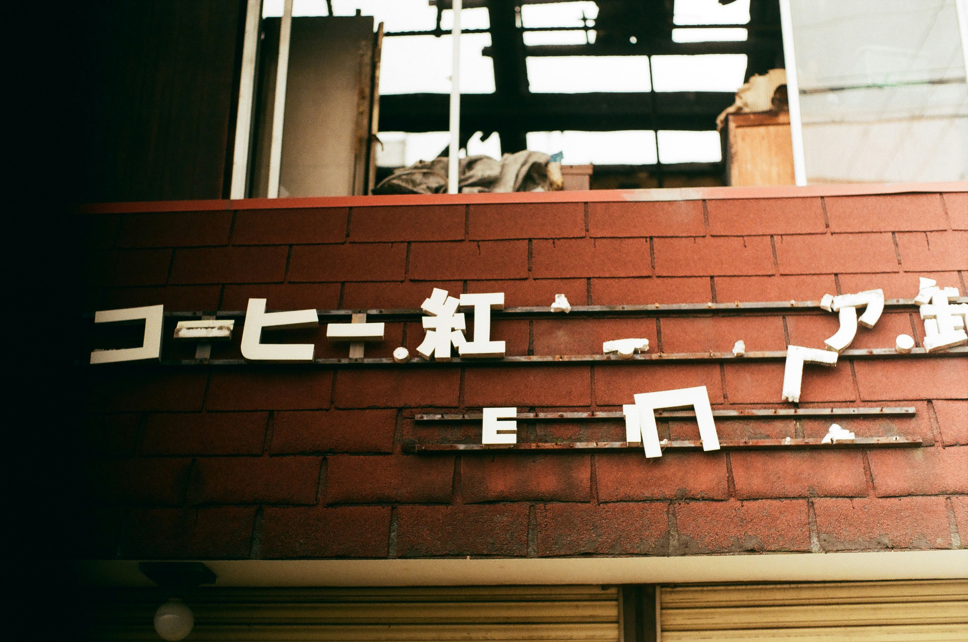 レンガ壁の喫茶店看板と煤けた文字のある路地の風景
