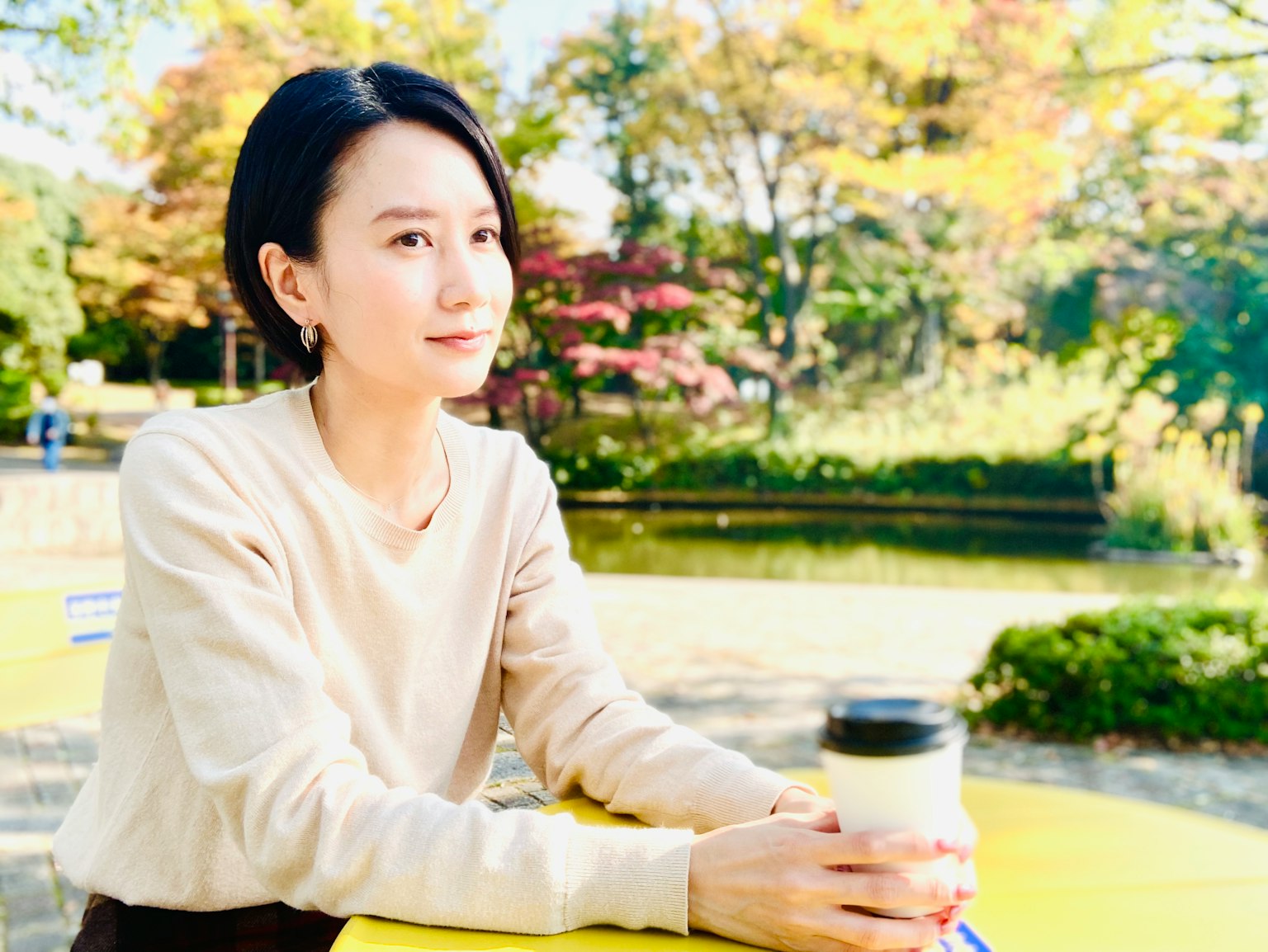 Chân dung một người phụ nữ cầm cà phê trong công viên với nền mùa thu đẹp