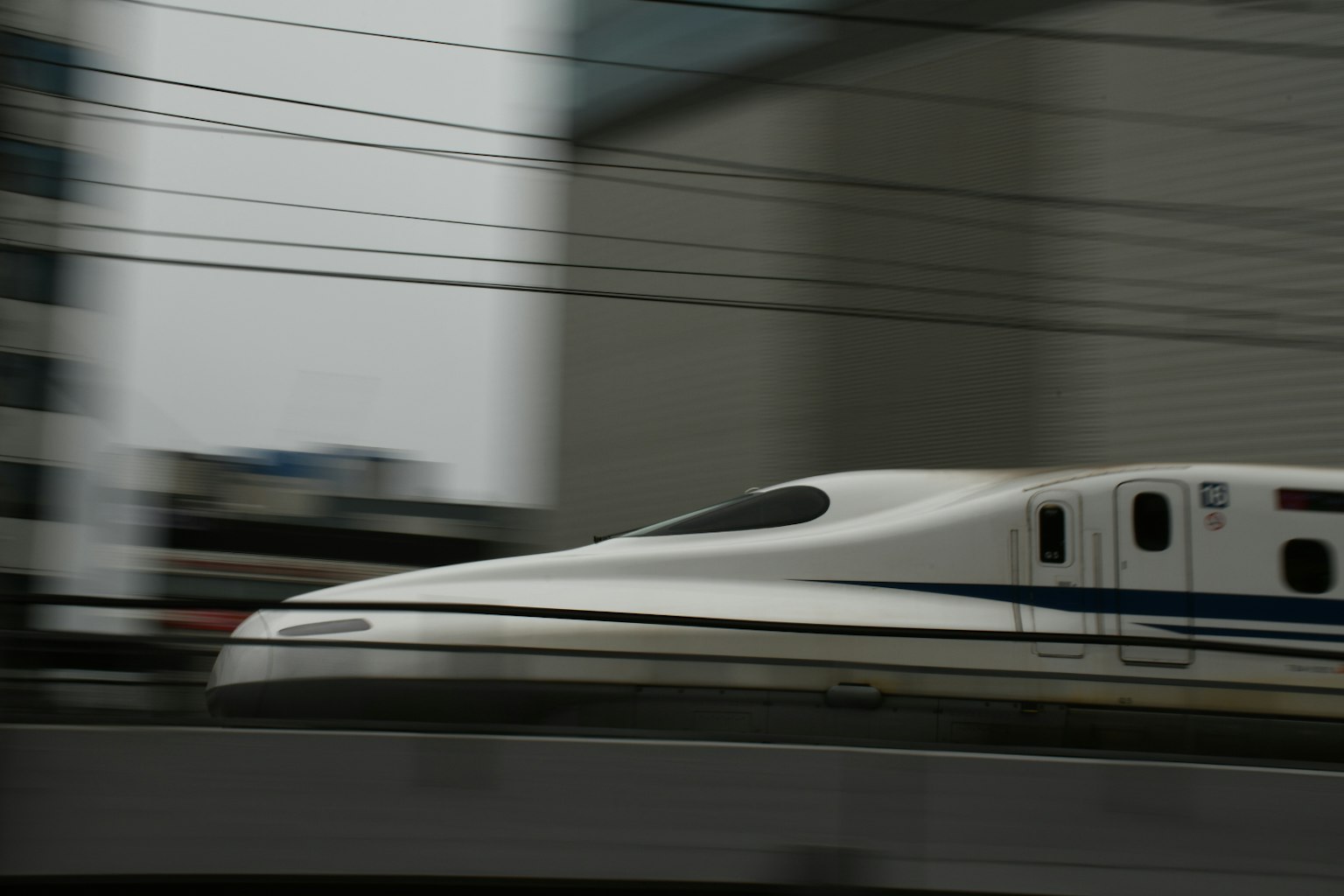 รถไฟชินคันเซ็นสีขาววิ่งอย่างรวดเร็วผ่านสภาพแวดล้อมในเมือง