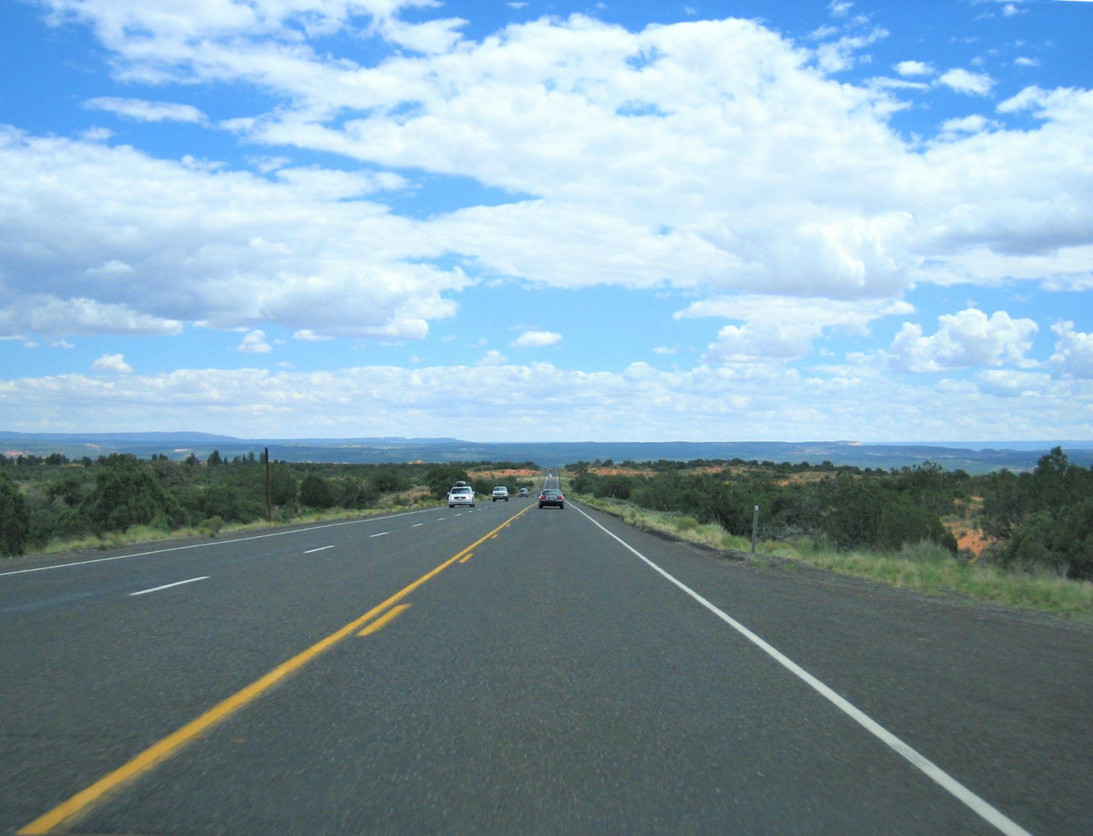 Carretera escénica con cielo azul claro y montañas distantes