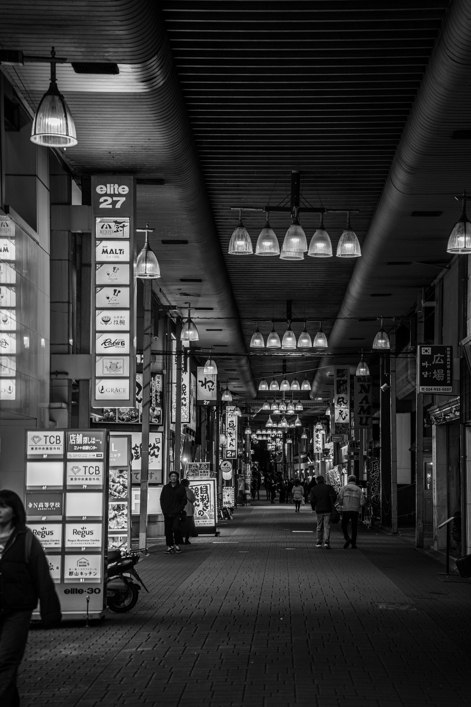 Rue commerçante en noir et blanc avec des lumières suspendues et des panneaux d'affichage le long des murs