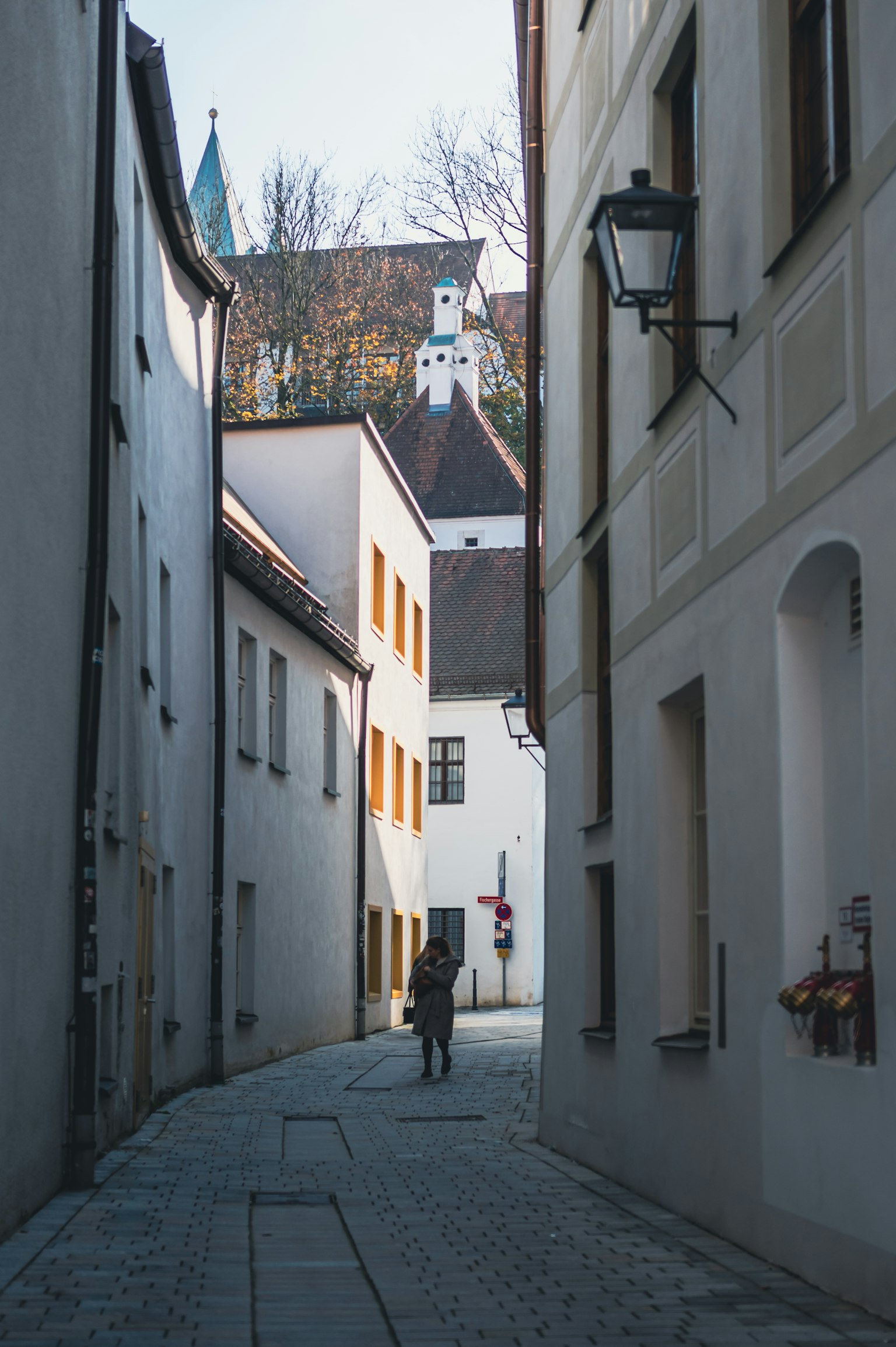 Narrow alley with a silhouette of a person and white buildings