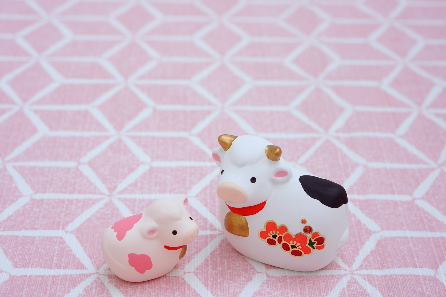Cute cow and pig figurines on a pink patterned background