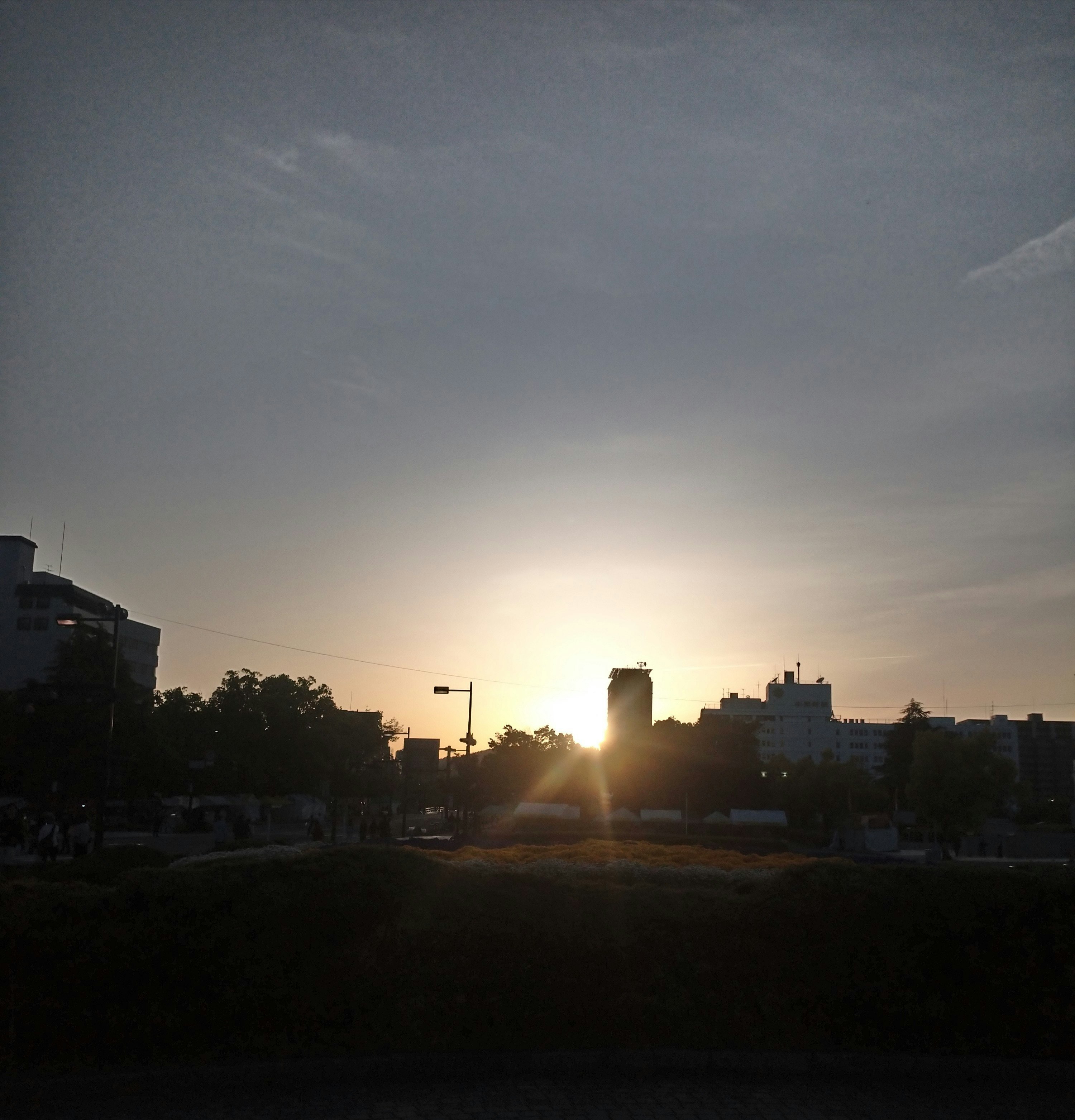 逆光の夕陽が差し込む空と街並みのシルエット
