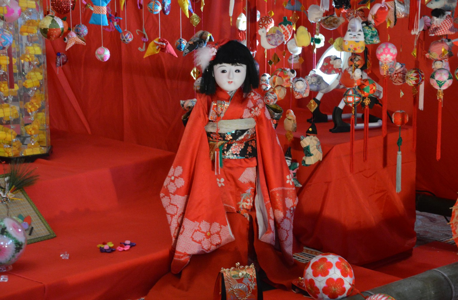 Búp bê mặc kimono đỏ được trưng bày giữa các trang trí đầy màu sắc