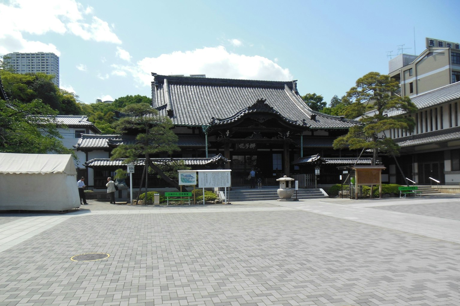 Eksterior kuil Jepang tradisional dikelilingi oleh pepohonan rimbun dan plaza