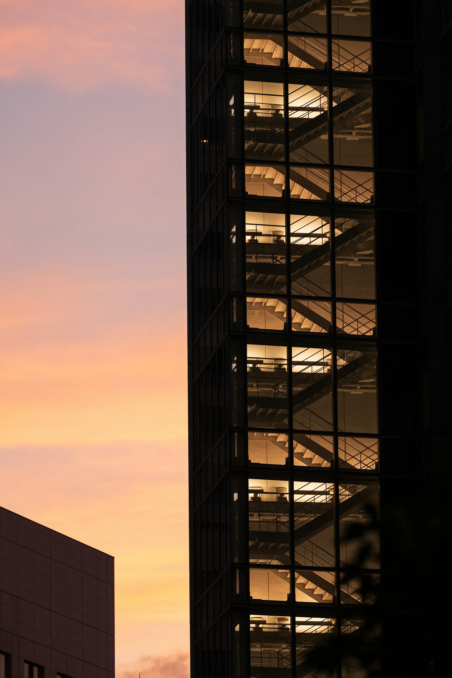 夕焼けの空を背景にしたガラスのビルの階段のシルエット