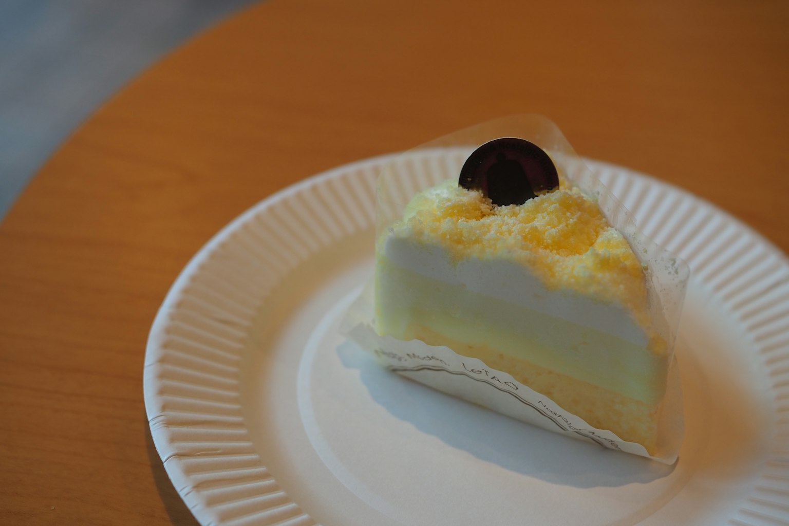 Une part de gâteau garnie de crème et d'un disque en chocolat