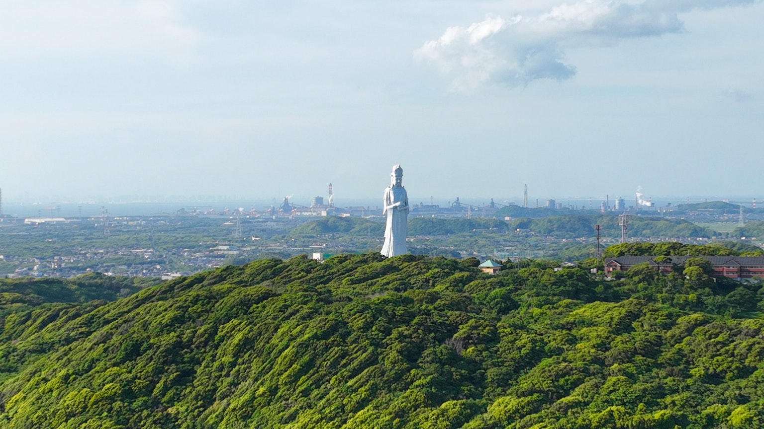 绿色山丘上的白色雕像与远处城市天际线