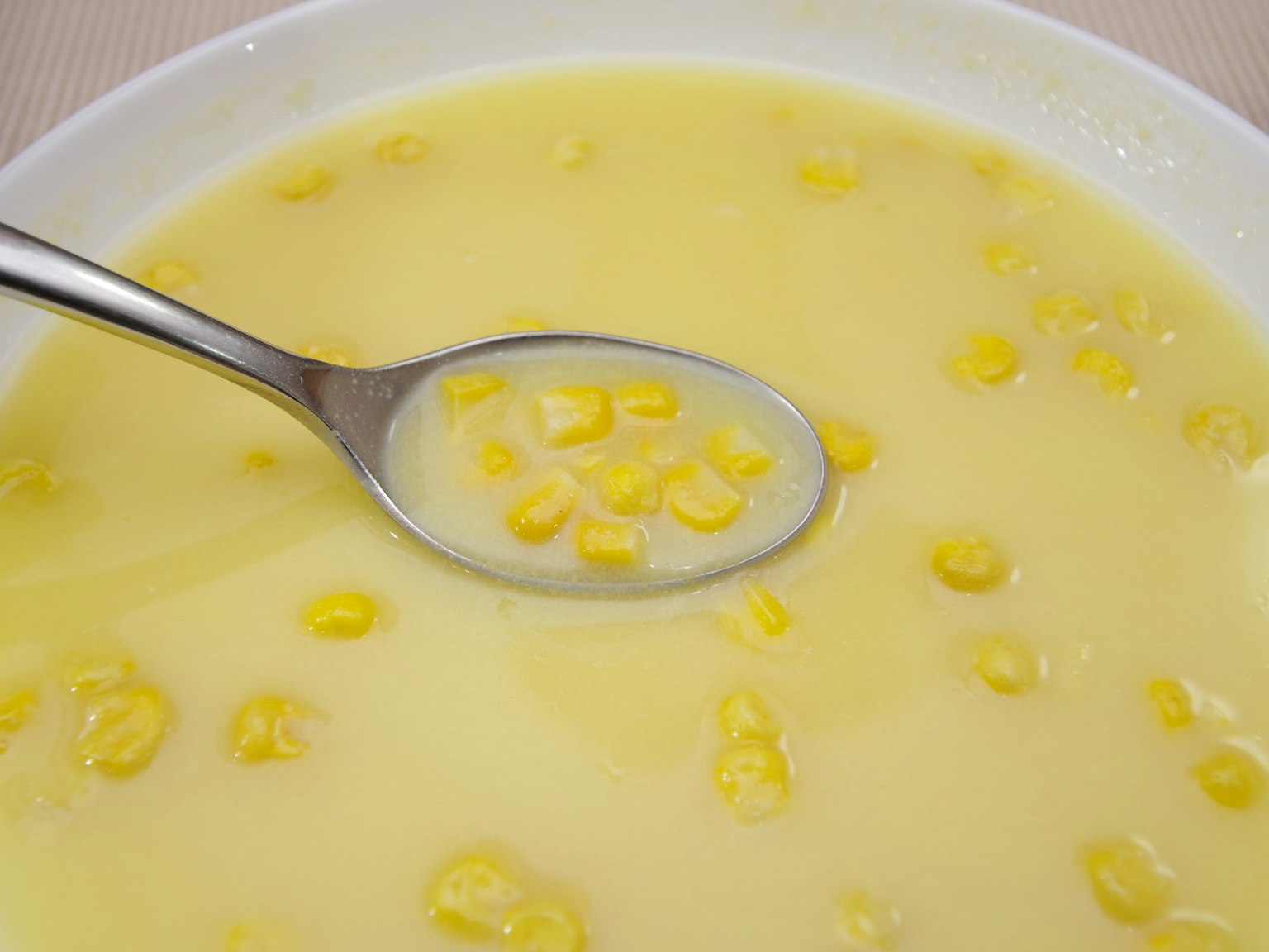 Image de soupe de maïs crémeuse avec des grains de maïs visibles et une cuillère