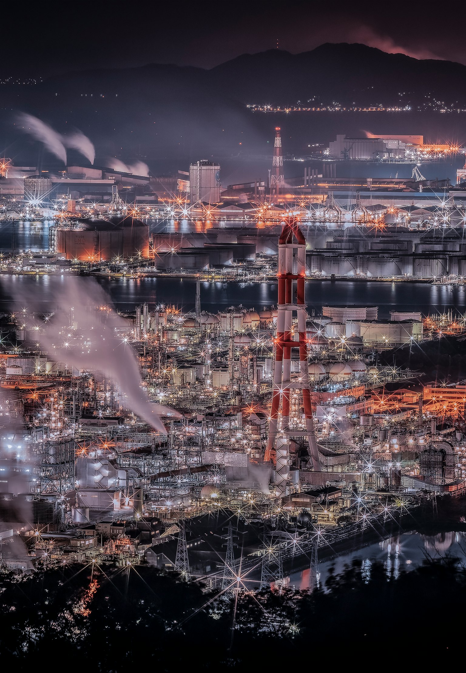 夜间工业区的壮观景色，工厂和烟囱被灯光照亮
