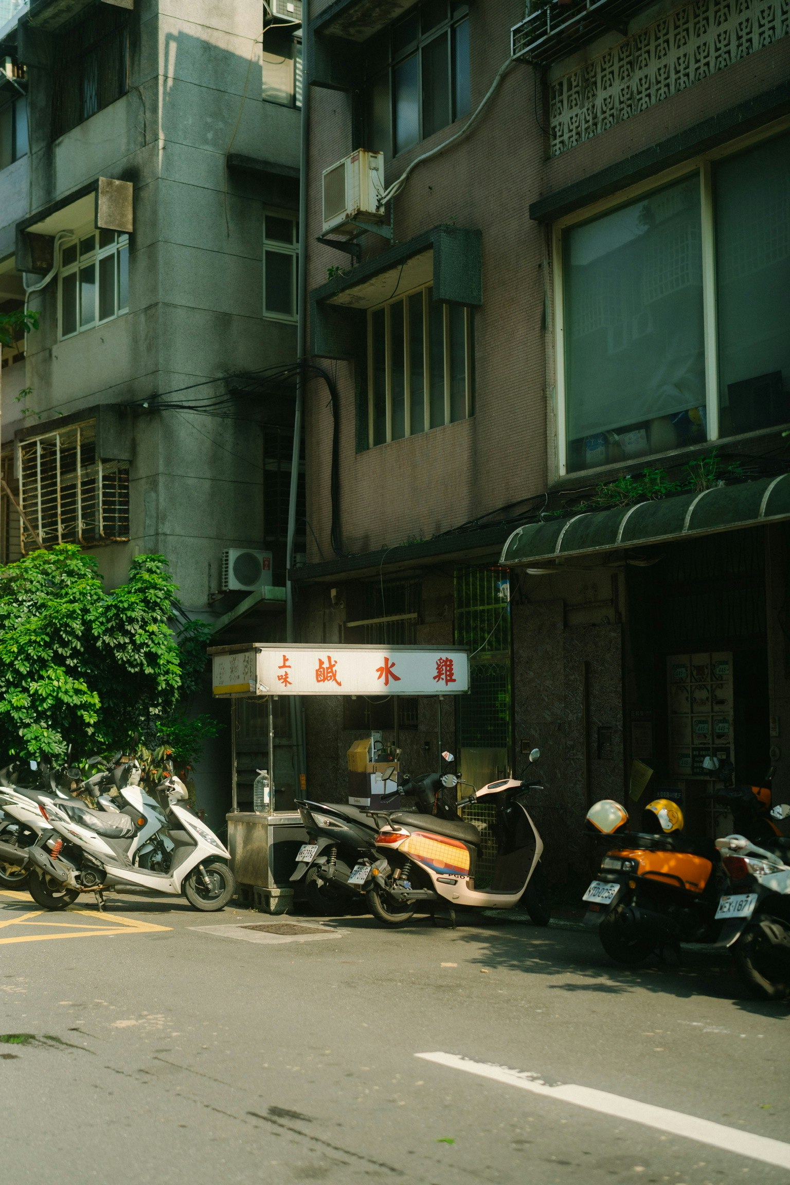 古い建物の前に並ぶバイクとスクーター 緑の植物が壁に絡まっている