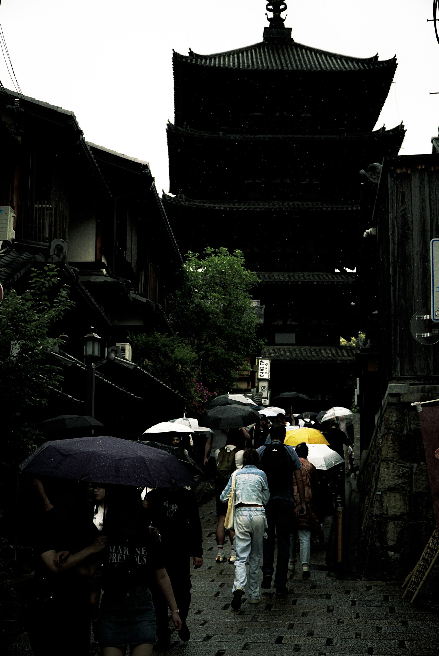 Des gens marchant sous la pluie avec des parapluies près de bâtiments traditionnels