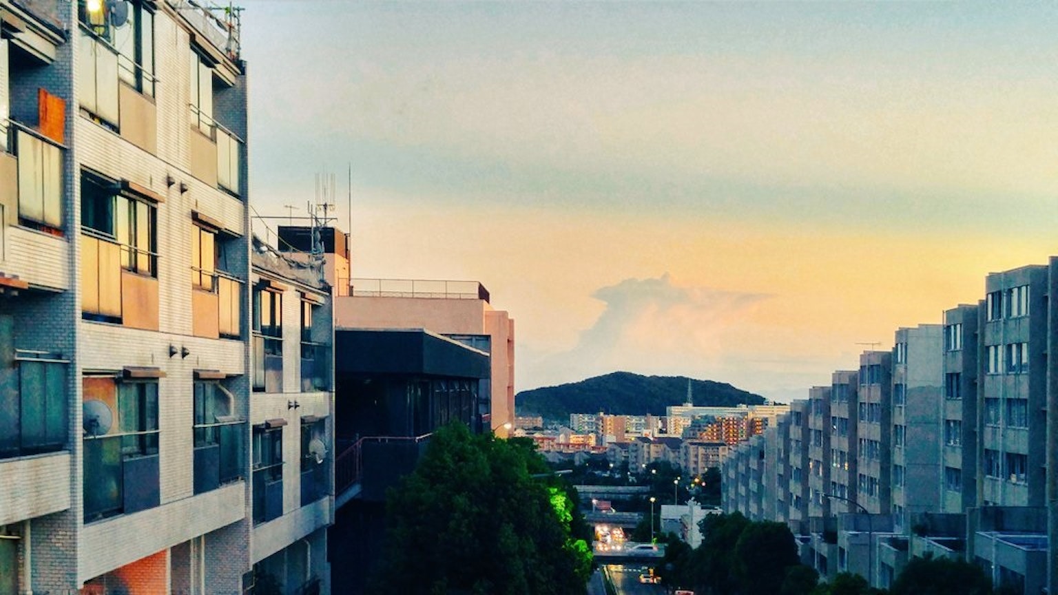 Cityscape at dusk featuring buildings and mountains