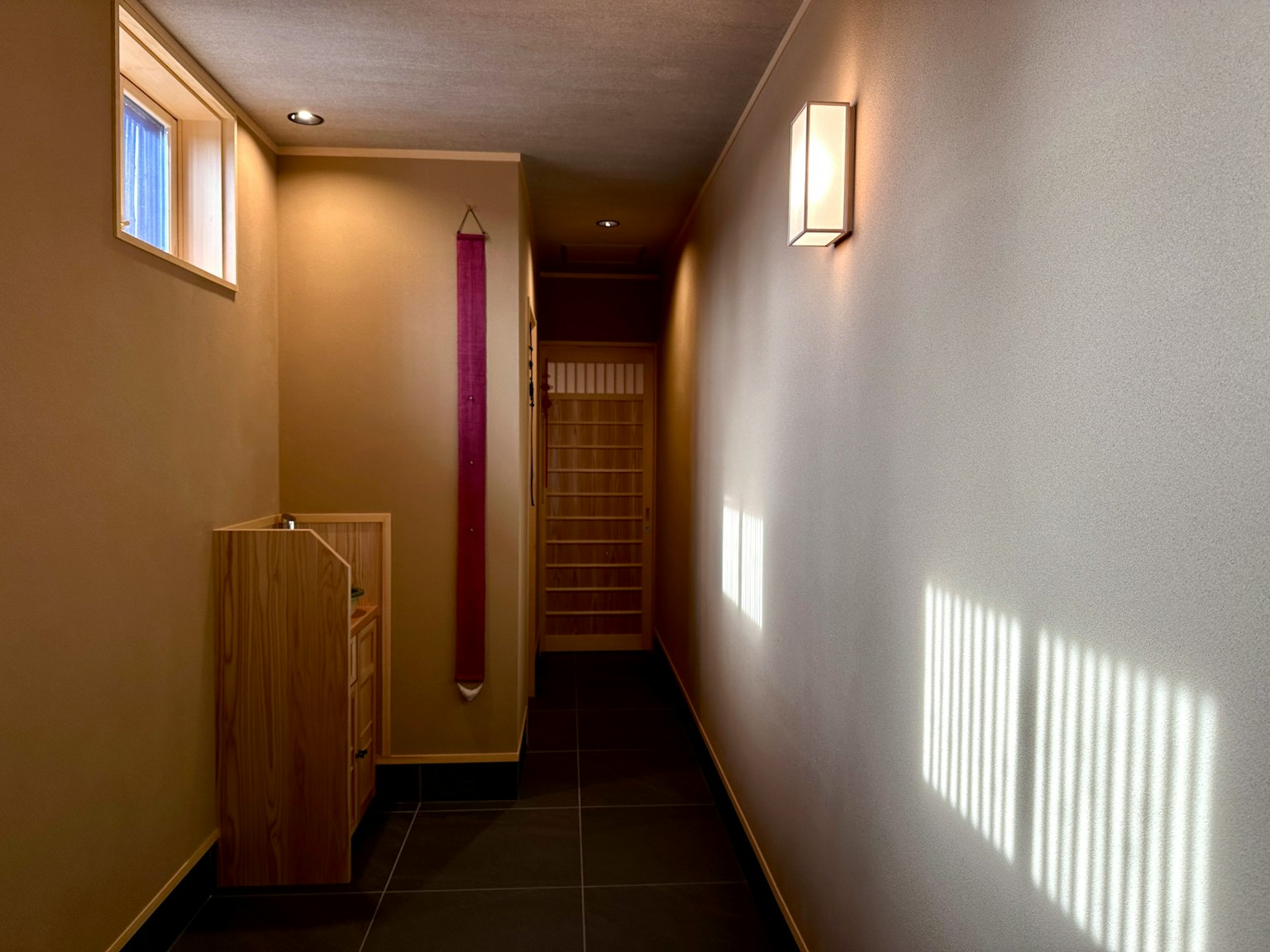 Lorong terang dengan jendela dan lampu dinding, lemari kayu dan ubin lantai