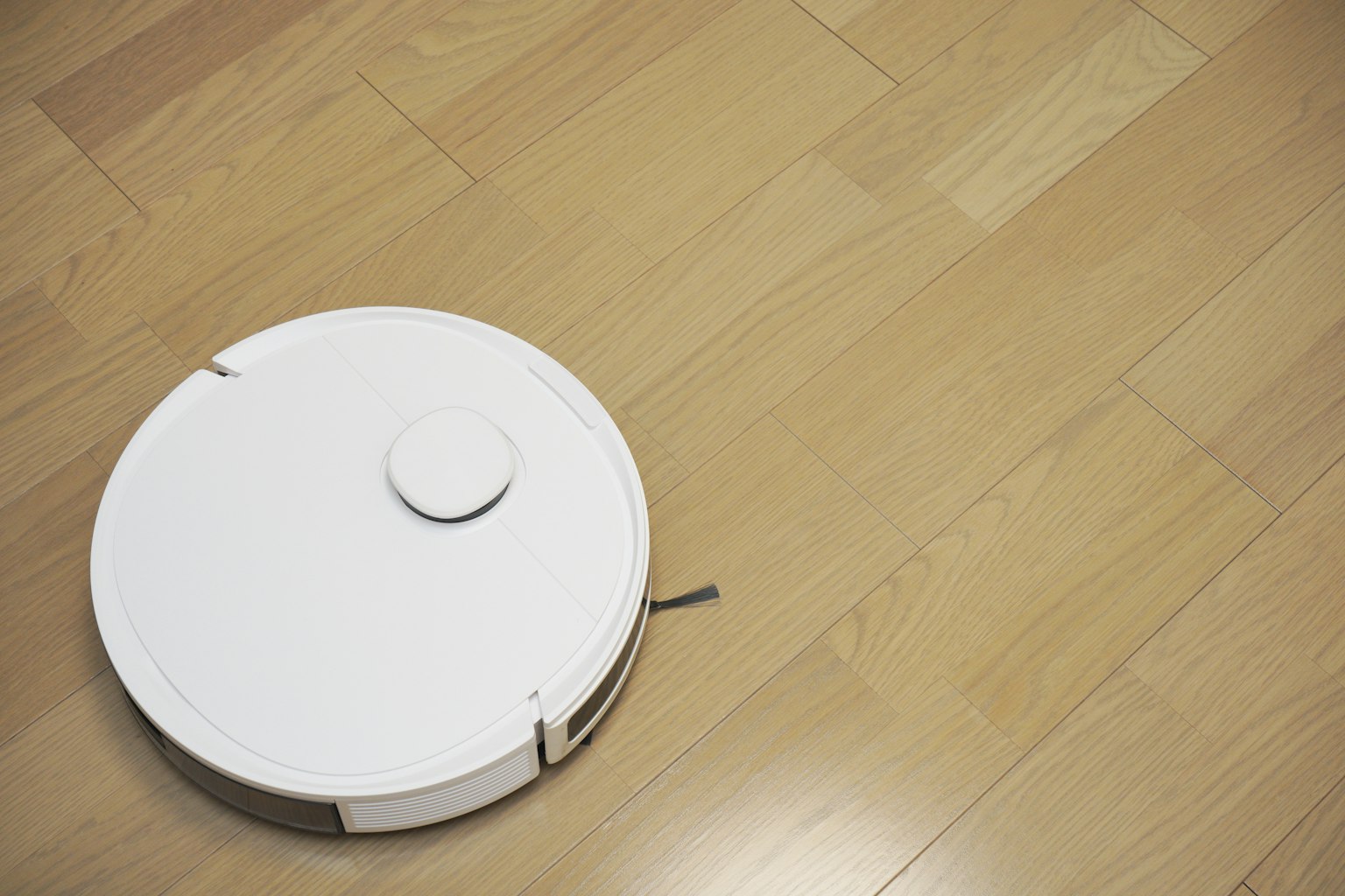 Un aspirateur robot blanc sur un sol en bois