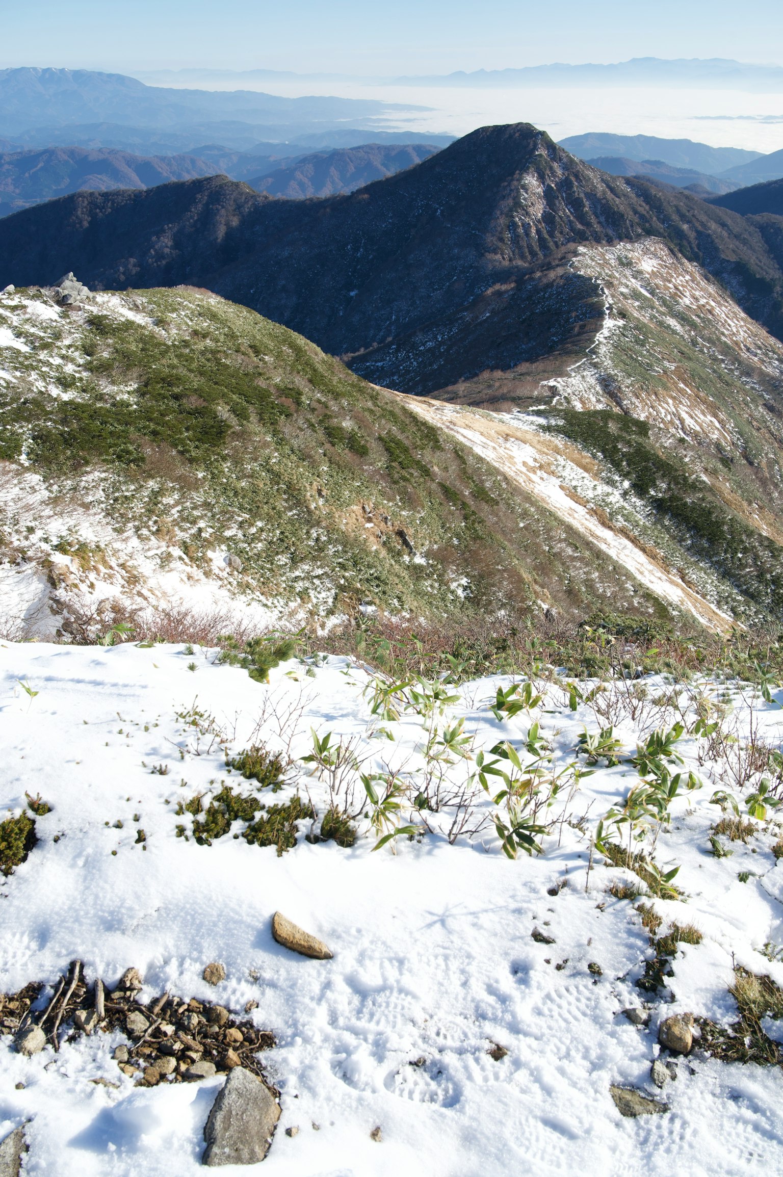 Pendio di montagna coperto di neve con picchi lontani visibili