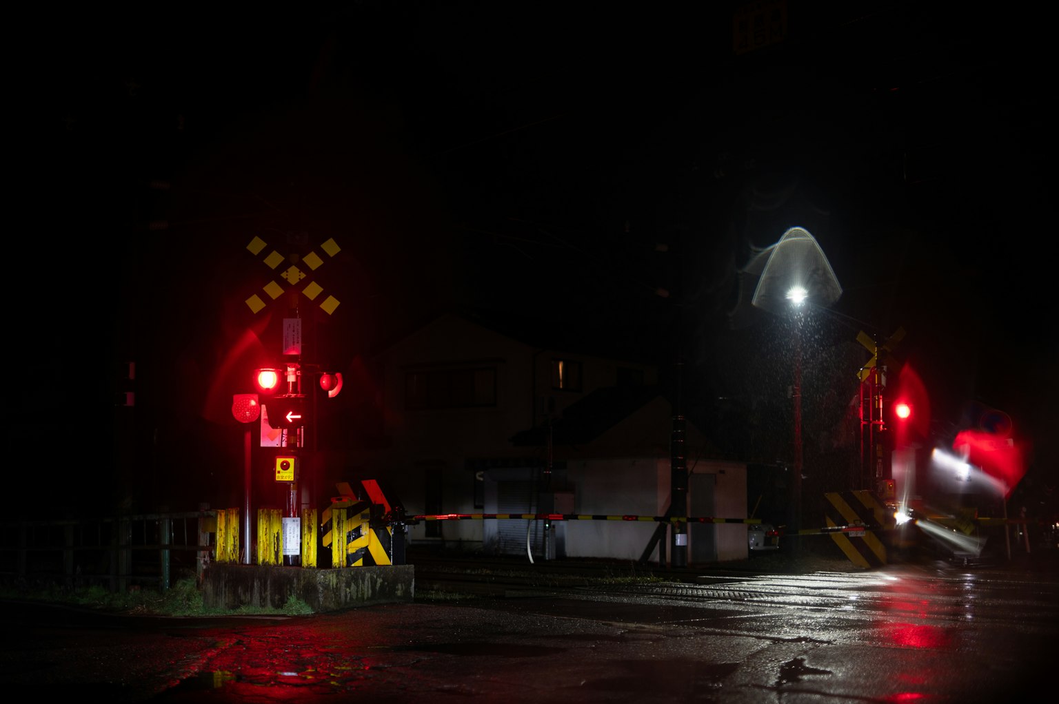 Cruce ferroviario nocturno con señales rojas y luces