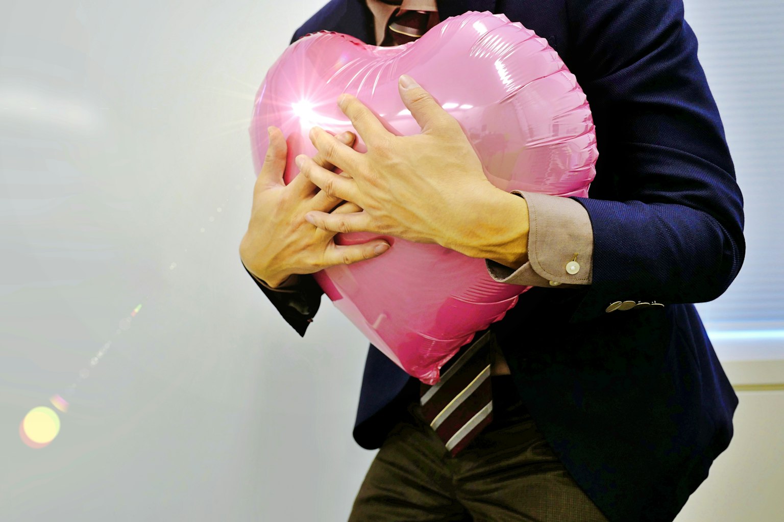 Seorang pria memeluk balon berbentuk hati berwarna pink