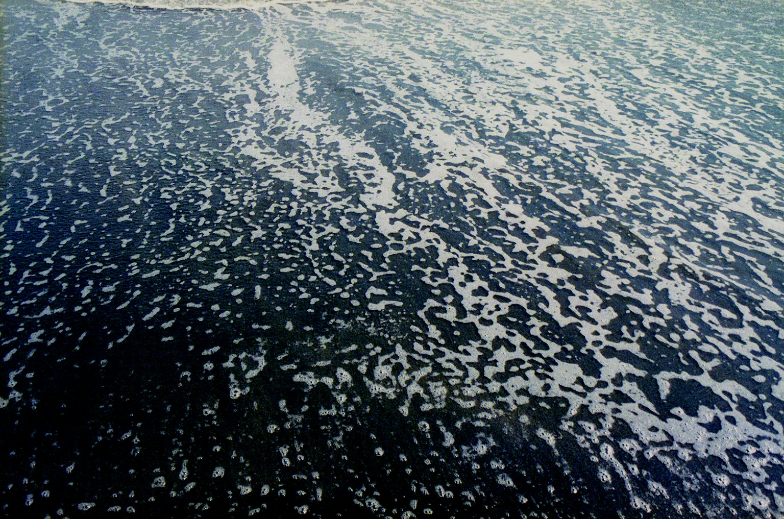 Surface d'eau bleue montrant des bulles et des motifs de vagues