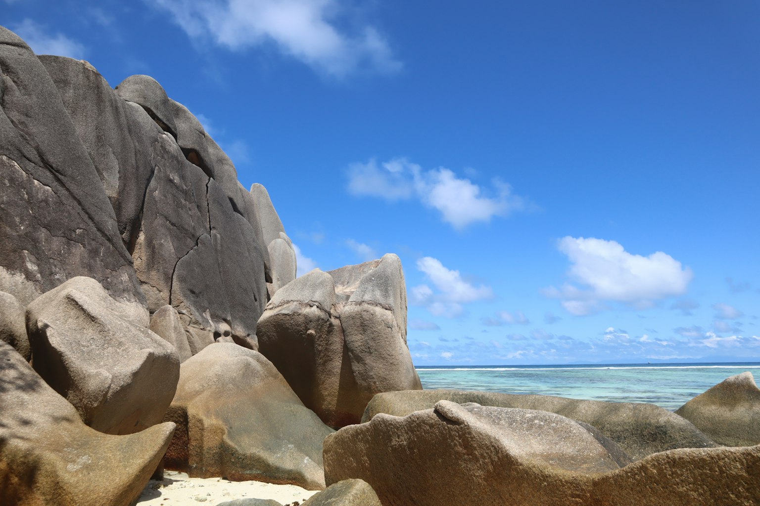 Beach scene with large rocks under a clear blue sky