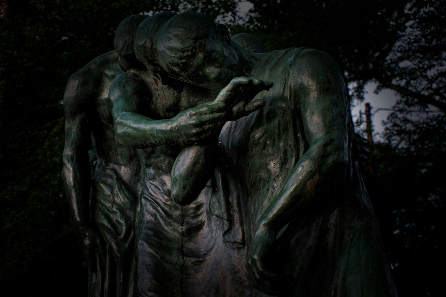 Statue von drei Figuren, die sich in einer dunklen Umgebung umarmen