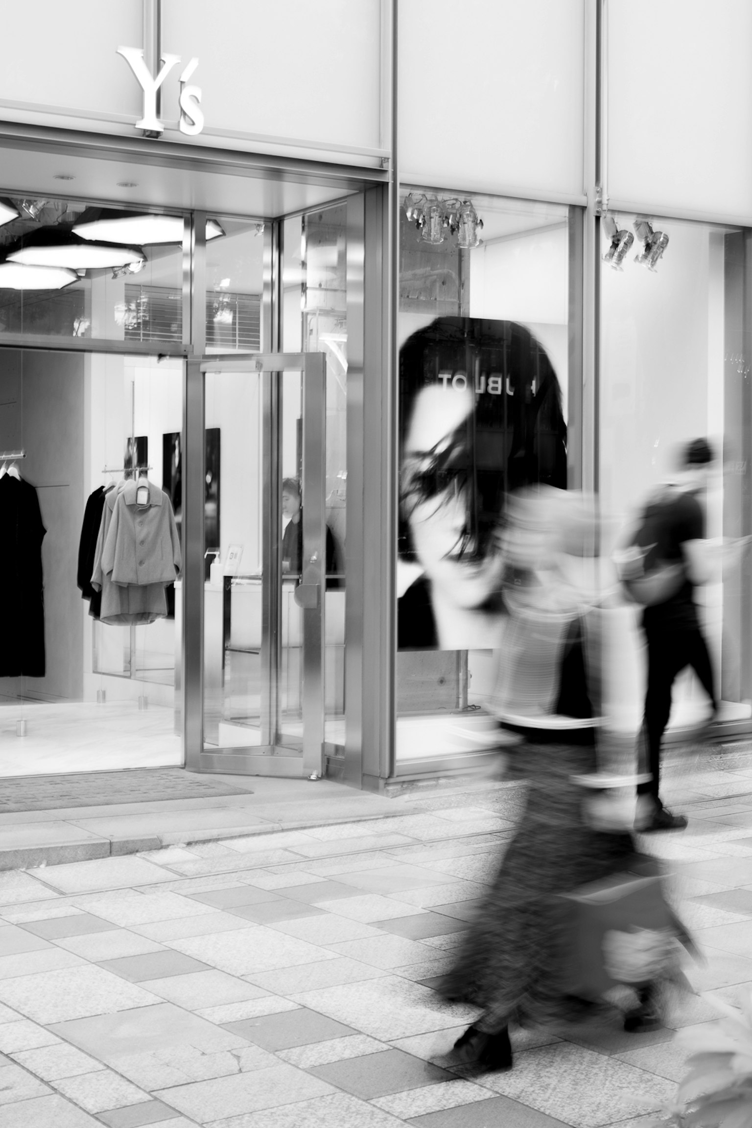 Imagen en blanco y negro de personas caminando frente a la tienda Ys