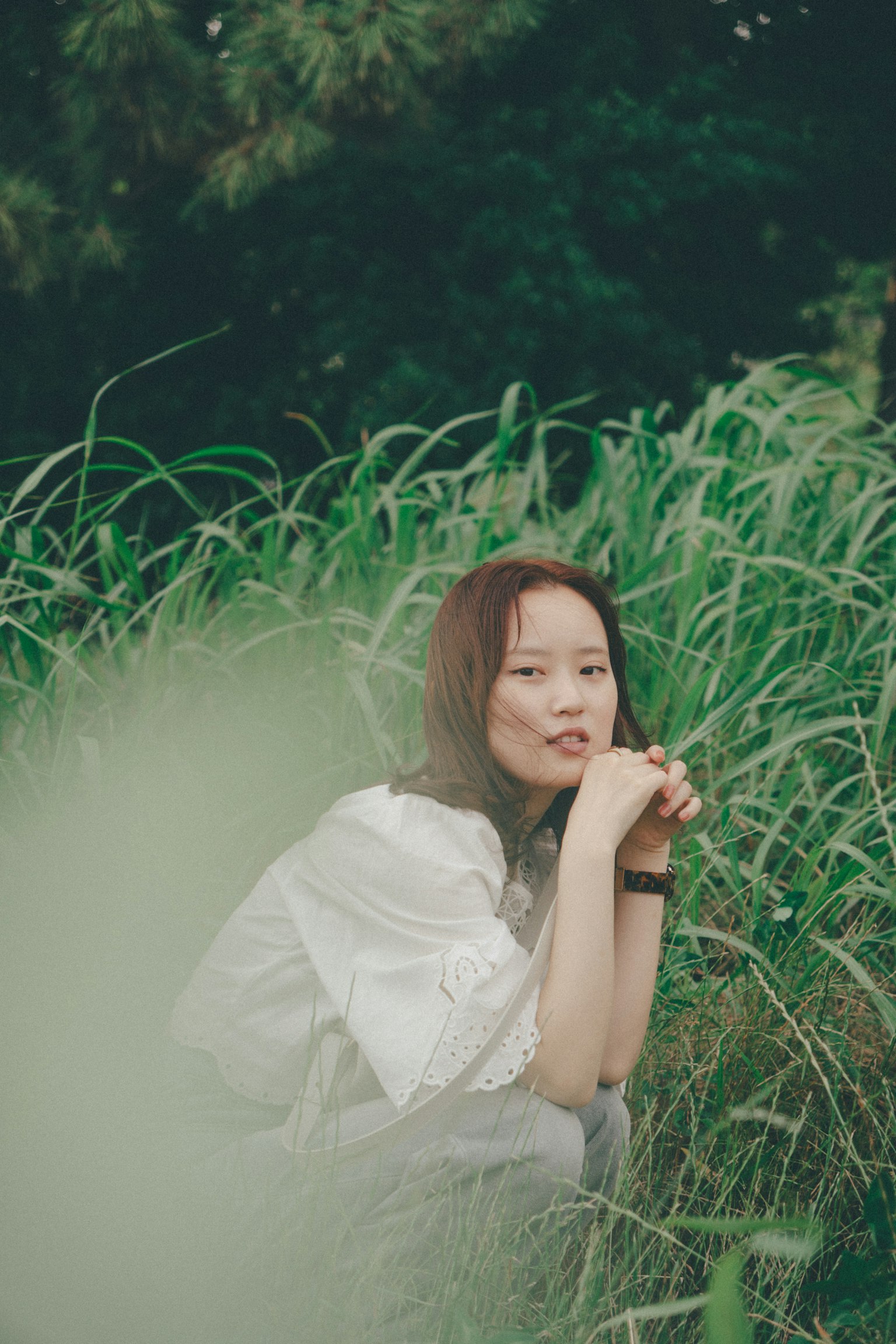 초록 들판에 앉아 있는 여성의 초상 화이트 의상을 입고 있음