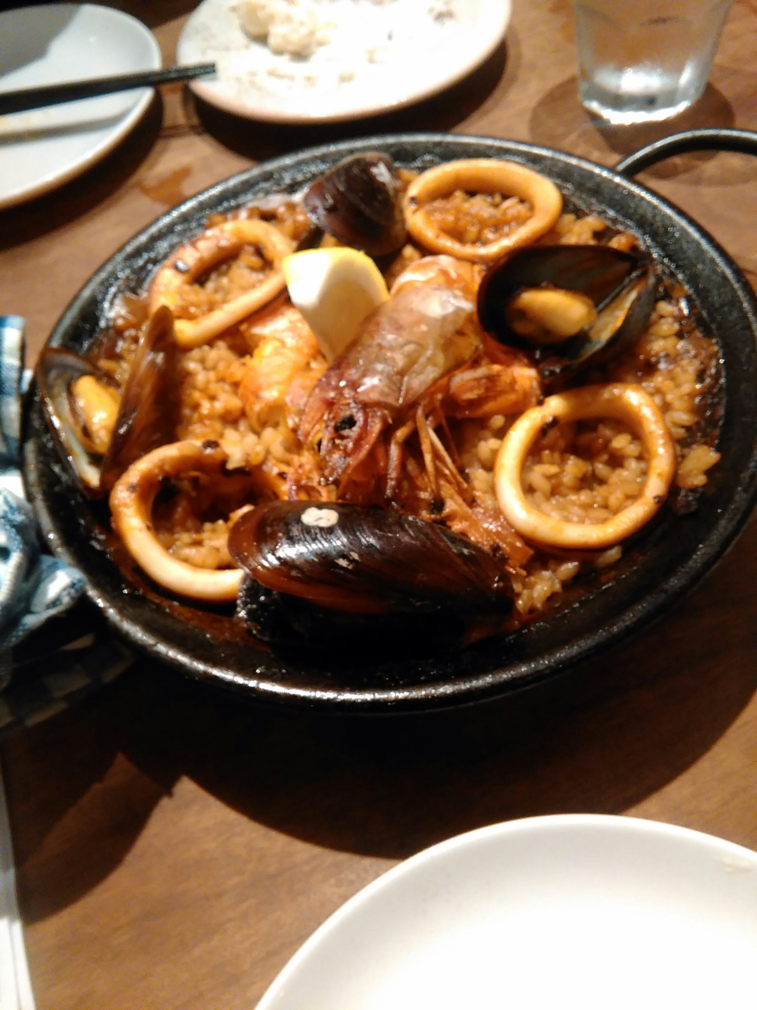 Un delicioso plato de paella con camarones, calamares y mejillones dispuestos de manera hermosa