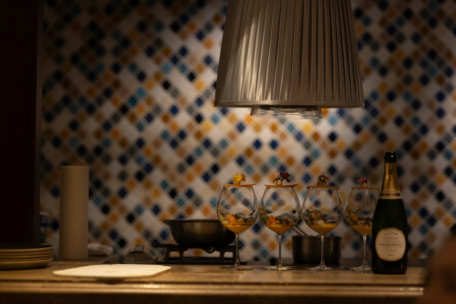 Set di champagne e bicchieri davanti a un muro piastrellato colorato