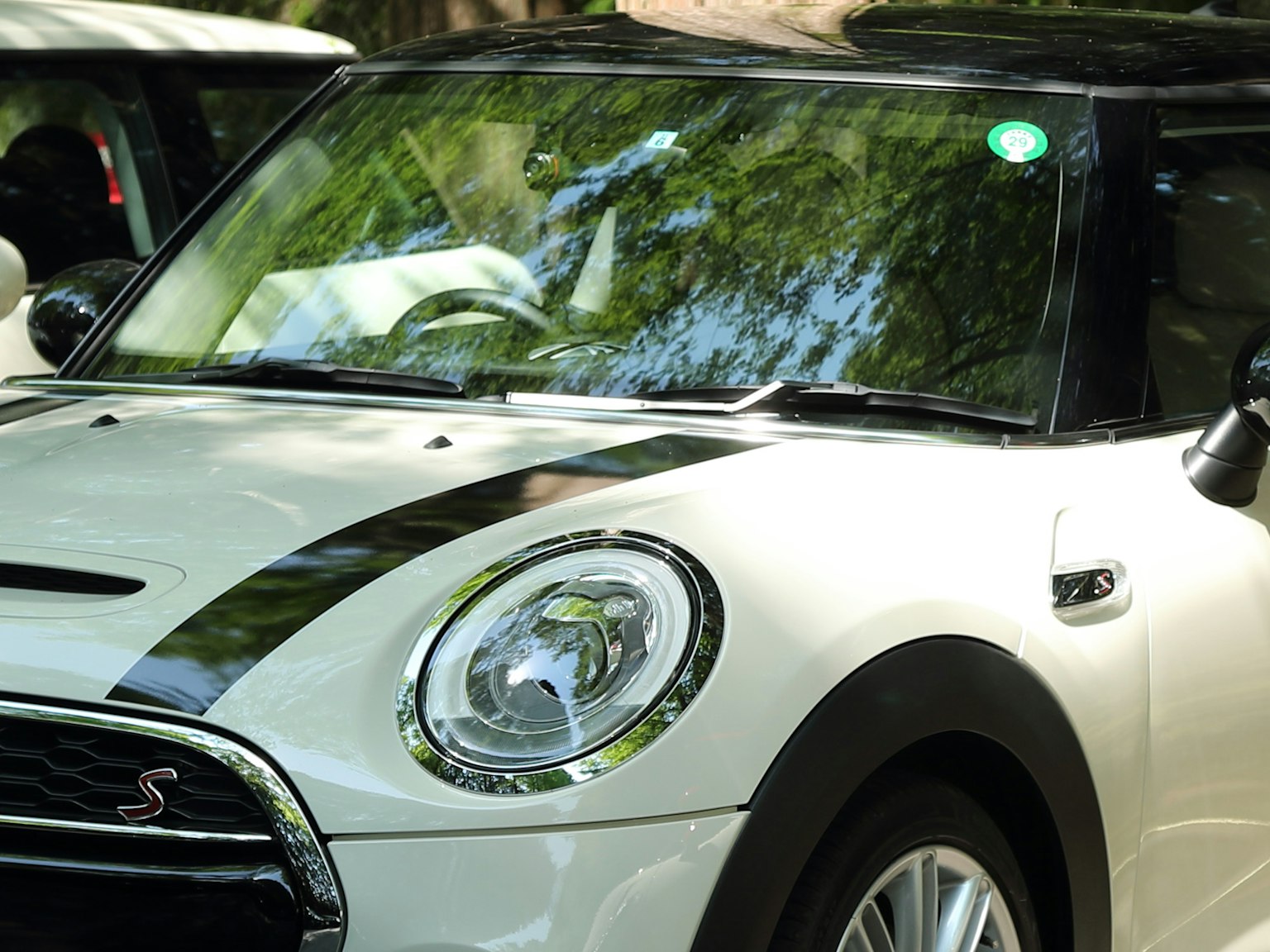 Góc nhìn phía trước của Mini Cooper màu trắng với sọc đen và đèn pha sáng bóng